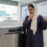 شابة سعودية تقف حائرة في متجر أجهزة منزلية أمام غسالة مواعين للمقارنة بين الماركات والأسعار.